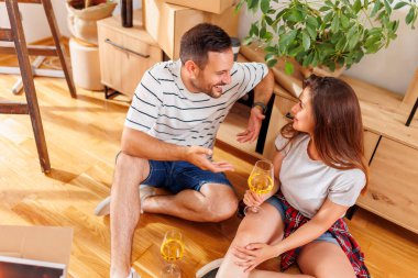 Yeni bir eve taşınıp, şarap içip, gülüp, eğlenen güzel genç çiftin manzarası.