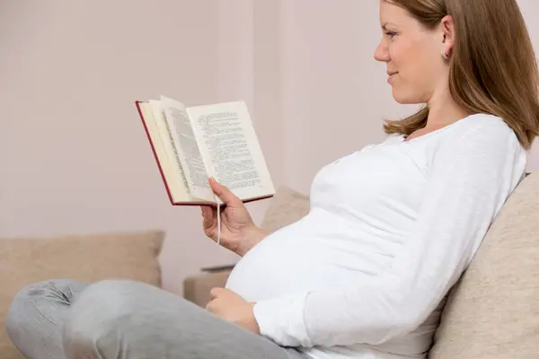 Oturma Odasındaki Kanepede Oturup Kitap Okuyan Güzel Hamile Kadın — Stok fotoğraf