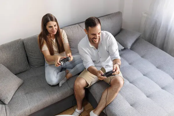 自宅で一緒にレジャー時間を過ごしながら楽しいビデオゲームをする愛の陽気なカップルのハイアングルビュー — ストック写真