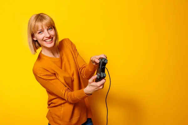 コピースペースで黄色の背景に隔離されたビデオゲームを楽しんでいる陽気な若い女性の肖像画 — ストック写真