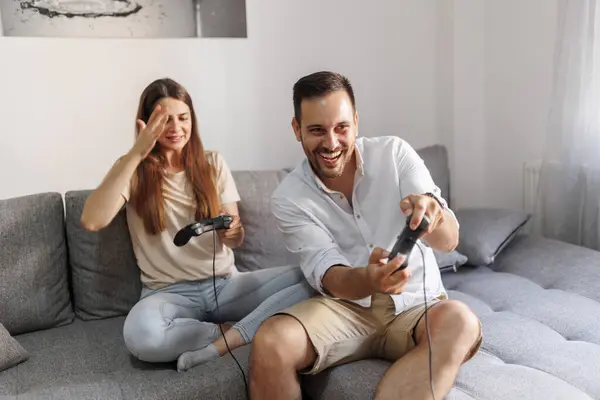 自宅で一緒にレジャー時間を過ごしながら楽しいビデオゲームをする愛の陽気なカップル — ストック写真