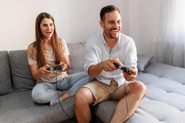 美しい若いカップルは 自宅で一緒にレジャー時間を過ごしながら 楽しいビデオゲームをするのが大好きです — ストック写真