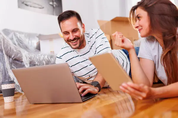 愛のカップルは一緒に移動し ラップトップとタブレットのコンピュータを使用してネットをサーフィンし 家の装飾アイデアを検索 — ストック写真