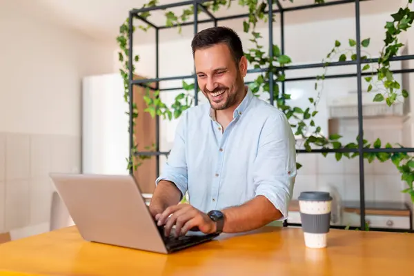 ラップトップコンピュータを使用して自宅のオフィスの机に座っているWeb開発者 自宅から遠隔で作業する男性 — ストック写真