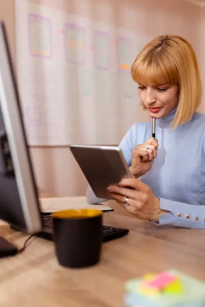 自宅のオフィスで机に座り タブレットコンピュータを使ってオンラインコースを受講し プランナーで執筆する女性 — ストック写真