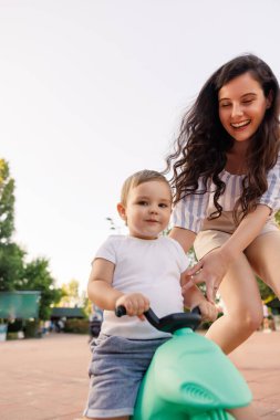 Güzel, genç bir anne dışarıda oğluyla vakit geçirip ona bisiklet sürmeyi öğretiyor.