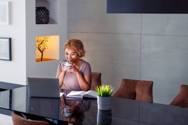 Ev bilgisayarını kullanan serbest çalışan bir kadın, evden uzakta çalışırken kahve içen bir kadın web tasarımcısı.