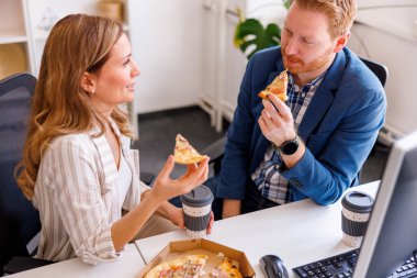 Yüksek açılı iş adamları ofiste öğle yemeği molası veriyor, pizza yiyor ve kahve içiyor.