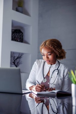 İnternette seminer veren kadın doktor, online kurs alırken not yazan, hastalarla görüntülü konuşma yapan ev ofisinden uzaktan çalışan.