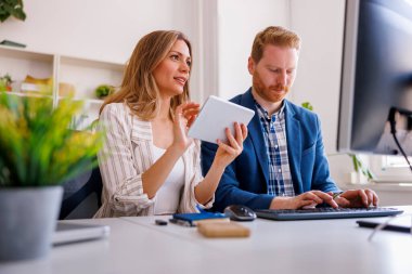 Bir ofiste birlikte çalışan programcılar, masa başında oturan, masaüstü ve tablet bilgisayarlar kullanarak kodları kodlayan ve gözden geçiren işadamları; 