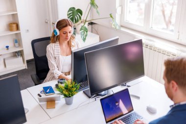 İş adamları masa başında oturuyor, ofiste çalışırken bilgisayar kullanıyorlar.
