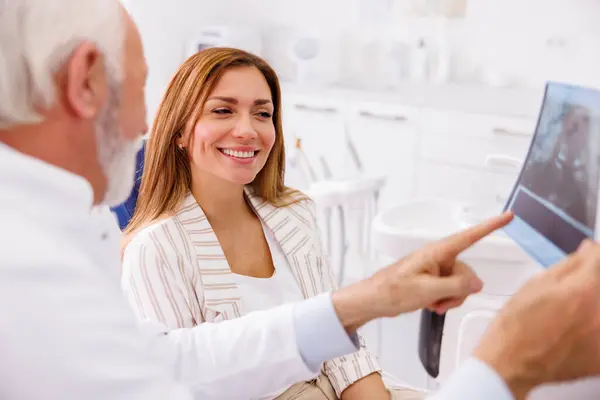 Tandläkare Förklara Nödvändiga Förfaranden För Patienten Sitter Tandstolen Medan Tittar Royaltyfria Stockfoton