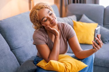 Güzel genç bir kadın evde dinlenirken selfie çekerek eğleniyor.