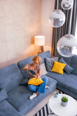 Güzel bir genç kadının evde dinlenirken selfie çekerken eğlendiği yüksek açılı manzara.