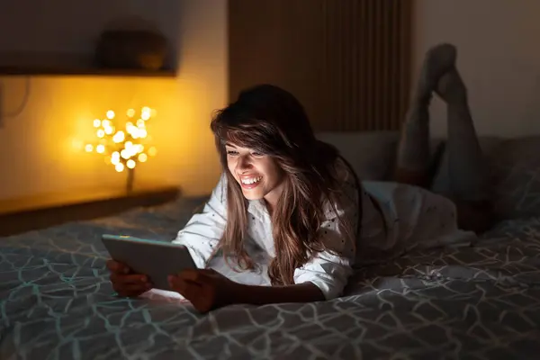 Piękna Kobieta Leży Łóżku Trzyma Tablet Komputera Czatując Online Pomocą — Zdjęcie stockowe