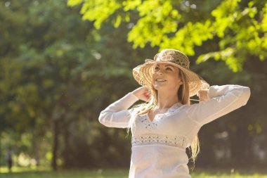 Güzel sarışın güneşli bir yaz gününde parkta eğleniyor.