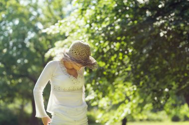 Güzel sarışın güneşli bir yaz gününde parkta eğleniyor, çimenlerde yürüyor.