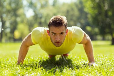 Parkta spor yapan genç bir sporcu, bir dizi şınav çekiyor.