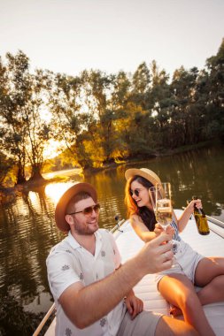 Birbirine aşık çiftler yaz tatilinin tadını çıkarıyorlar, kadeh kaldırıyorlar ve gün batımına doğru yelken açıyorlar.