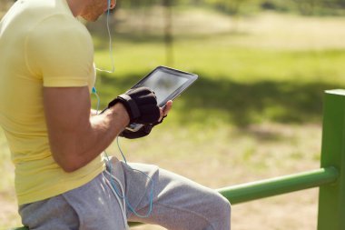 Sıkı bir egzersizden sonra, müzik dinleyip, tablet bilgisayarda internette sörf yapan genç bir sporcu.