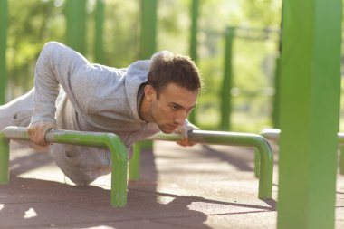 Genç sporcu dışarıda spor yapıyor, bir dizi şınav çekiyor.