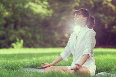 Orta yaşlı kadın Yoga sabah erken bir parkta yapıyor.