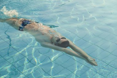 Genç adam yüzme havuzunda antrenman yapıyor.