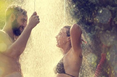 Genç çift yüzdükten sonra sahilde duş alıyor.