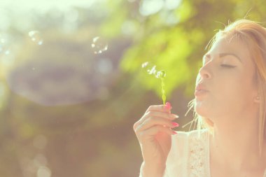 Sabun köpüğü üfleme parkta bir güneşli yaz gününde güzel bir genç kadının portresi