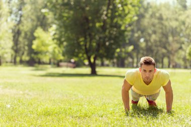 Parkta spor yapan genç bir sporcu, bir dizi şınav çekiyor.