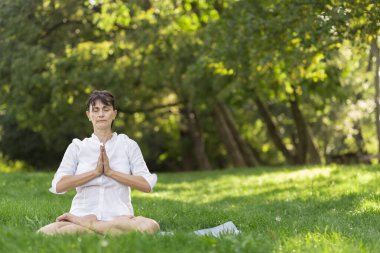 Orta yaşlı kadın Yoga sabah erken bir parkta yapıyor.
