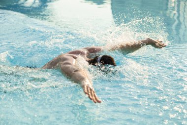 Genç adam yüzme havuzunda antrenman yapıyor.