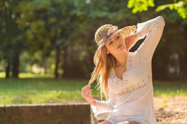 Güzel sarışın güneşli bir yaz gününde parkta eğleniyor.