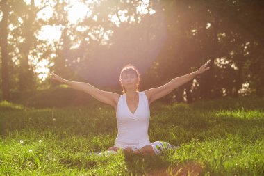 Orta yaşlı kadın Yoga sabah erken bir parkta yapıyor.