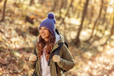 Sırt çantası taşıyan aktif genç bir kadın doğa da güzel bir sonbahar gününün tadını çıkarıyor.