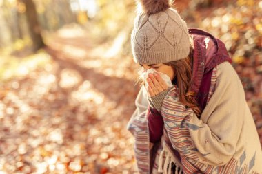 Kadın soğuk aldı, güneşli bir sonbahar gününü dışarıda geçirirken burnunu sümkürdü.