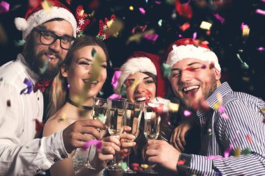 Yılbaşı partisinde kadeh kaldıran bir grup genç arkadaş gece yarısı şampanya kadehleri kaldırıyor.