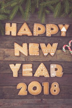 Güzel dekore edilmiş Noel kurabiyelerinin masa başı fotoğrafı. Harf şeklinde. Şeker kamışı ve köknar ağacı dallarıyla mutlu 2018.