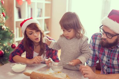 Güzel, genç bir aile Noel kurabiyesi pişirirken eğleniyor.