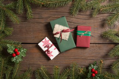 Çam dallarından yapılmış bir çerçevenin üst görüntüsü ökse parmaklarıyla süslenmiş çerçevenin içine güzelce paketlenmiş hediye kutuları yerleştirilmiş.