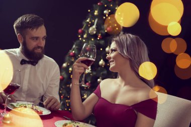 Birbirine aşık bir çift romantik bir Noel yemeği yerken kadeh kaldırıyor. Kıza odaklan.