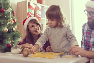 Güzel, genç bir aile Noel kurabiyesi pişirirken eğleniyor. Annesine odaklan.