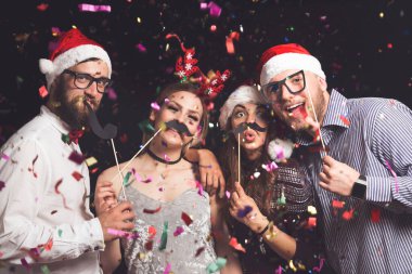 Yılbaşı partisinde maskeli fotoğraflara poz veren dört genç arkadaş.