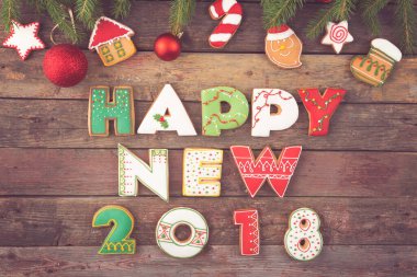 Güzel dekore edilmiş Noel kurabiyelerinin masa başı fotoğrafı. Harf şeklinde. Madalyalı köknar ağacı dallarıyla mutlu 2018.