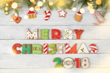 Güzel dekore edilmiş Noel kurabiyelerinin üst manzarası harf şeklinde Mutlu Noeller 2018 Çam brunch 'ları, şeker kamışı ve beyaz ahşap arka planda ökseotu