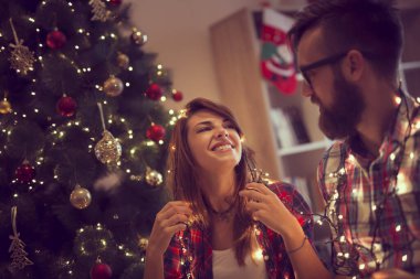 Noel ağacı süsleme, Noel ışıkları düzenlenmesi ve having fun aşık güzel genç Çift