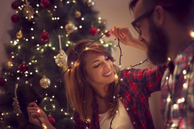 Noel ağacı süsleme, Noel ışıkları düzenlenmesi ve having fun aşık güzel genç Çift