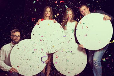 Yılbaşı arifesini kutlayan bir grup güzel genç, ellerinde dört tane boş mukavva daire tutuyor.