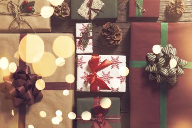 Ön planda Noel ışıkları olan güzel paketlenmiş hediye kutularının olduğu masa resmi. Ortadaki zamana odaklan.