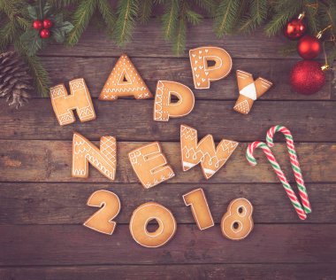 Güzel dekore edilmiş Noel kurabiyelerinin masa başı fotoğrafı. Mektuplar şeklinde. Şeker kamışı, kozalak ve köknar ağacı dallarıyla mutlu 2018.